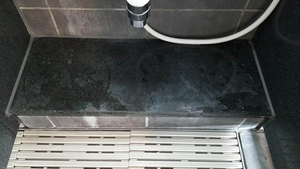 ハンドポリッシャーを使ってホテル大浴場洗い場カウンターの黒御影石の磨き方を講習する磨学校